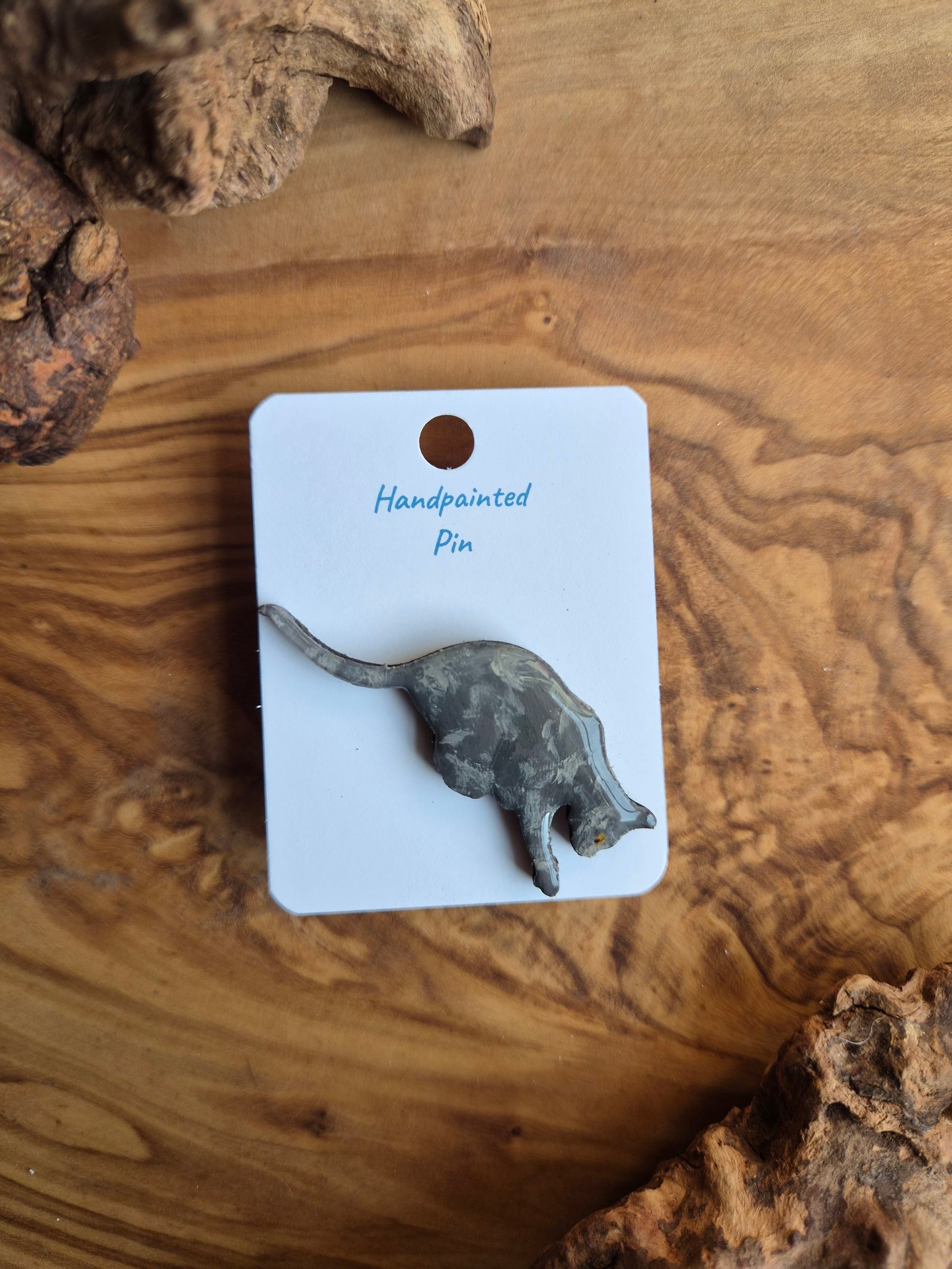 Hand-painted wooden pin badge of a dilute tortoiseshell coloured cat jumping down