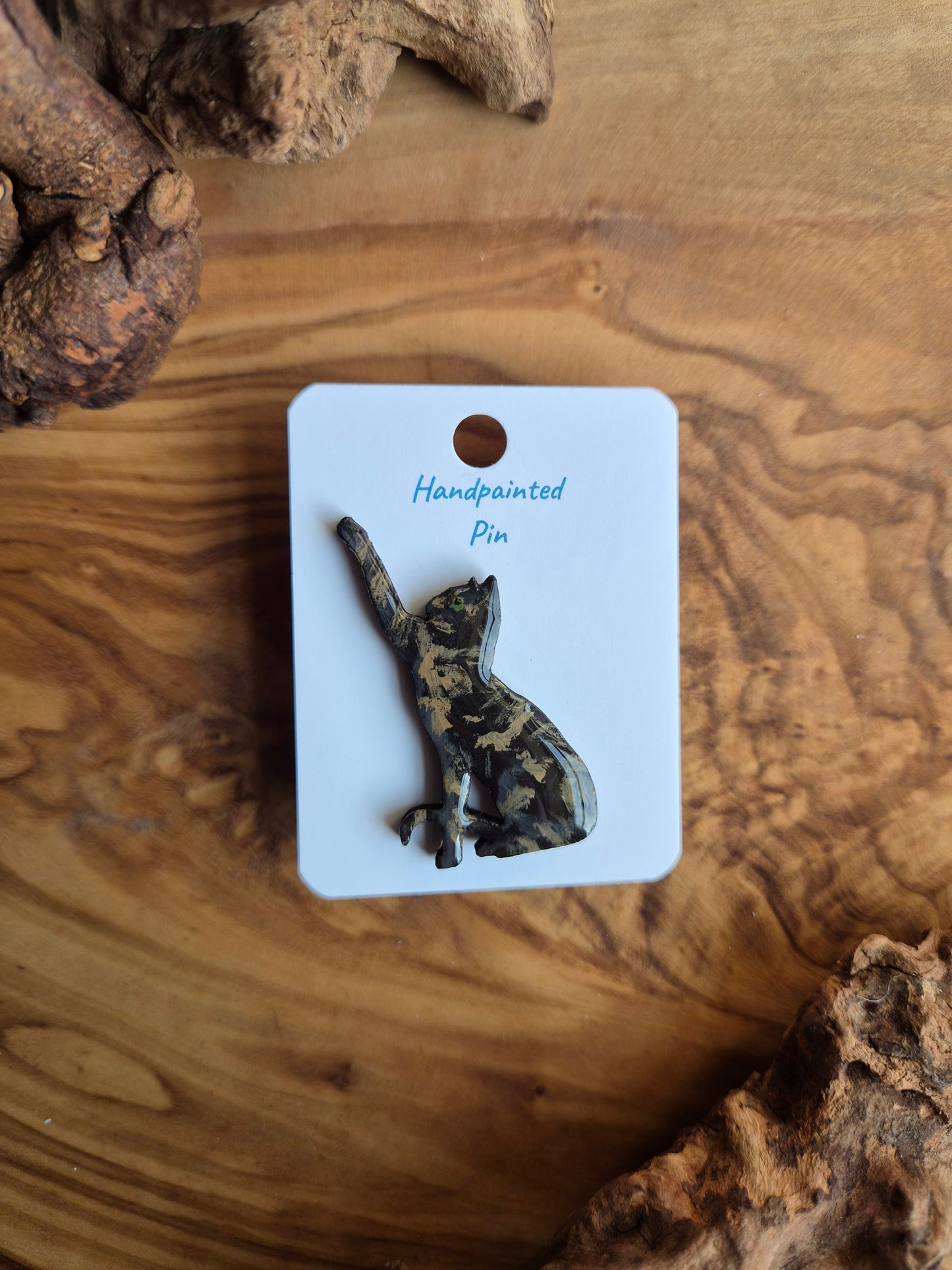 Hand-painted wooden pin badge of a  tortoiseshell coloured cats pawing