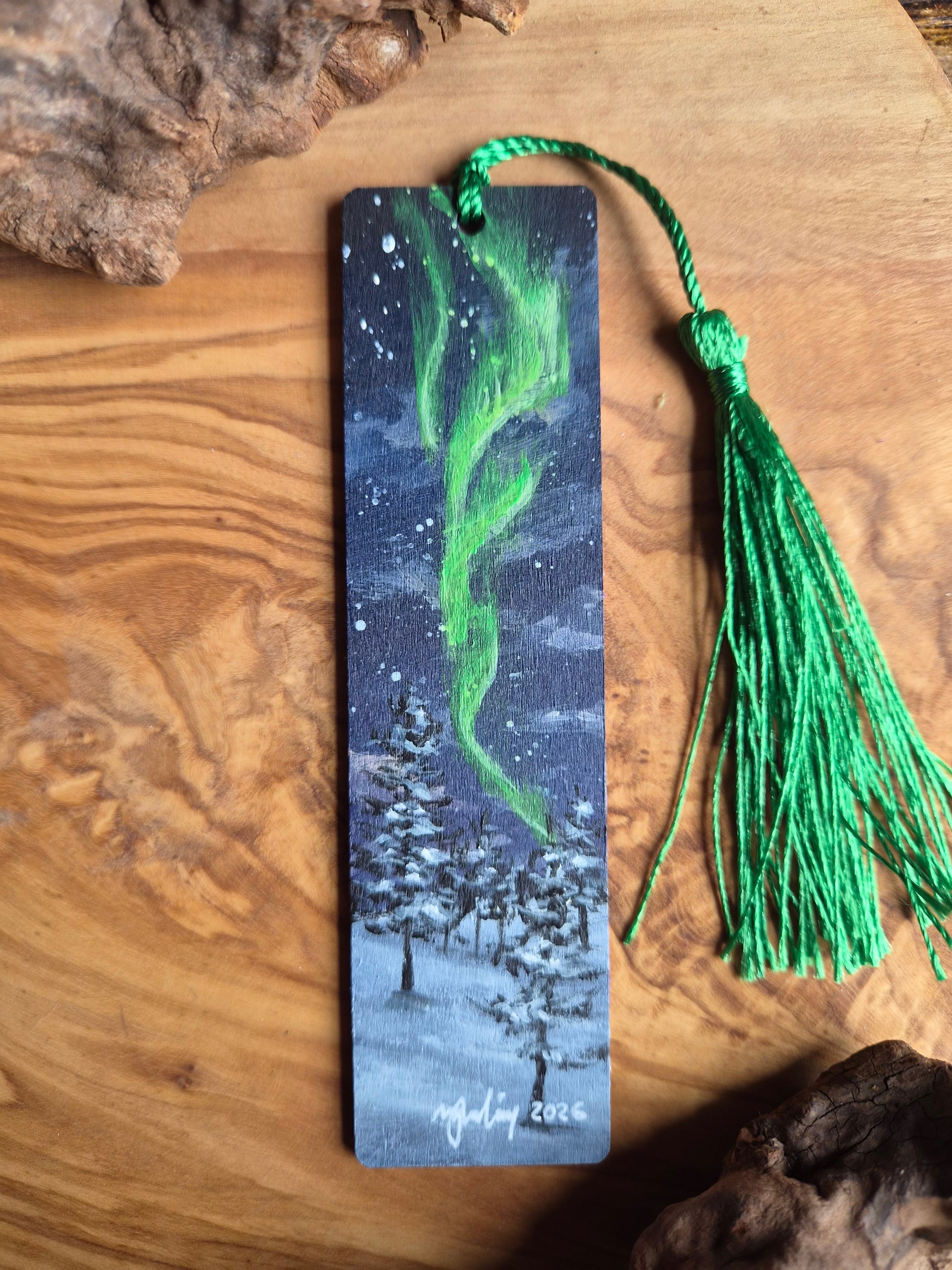 Hand-painted wooden bookmark of the northern lights in a snowy forest