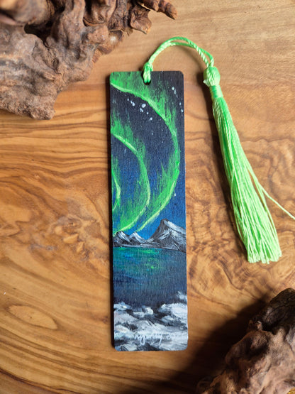 Hand-painted wooden bookmark of the northern lights with distant snowy mountains