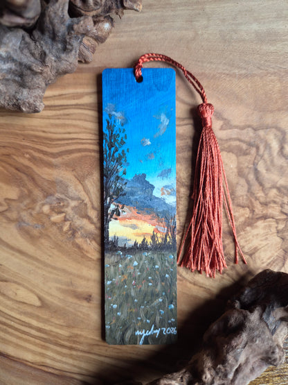 Bookmark with a scenic sunset painting on a wooden surface