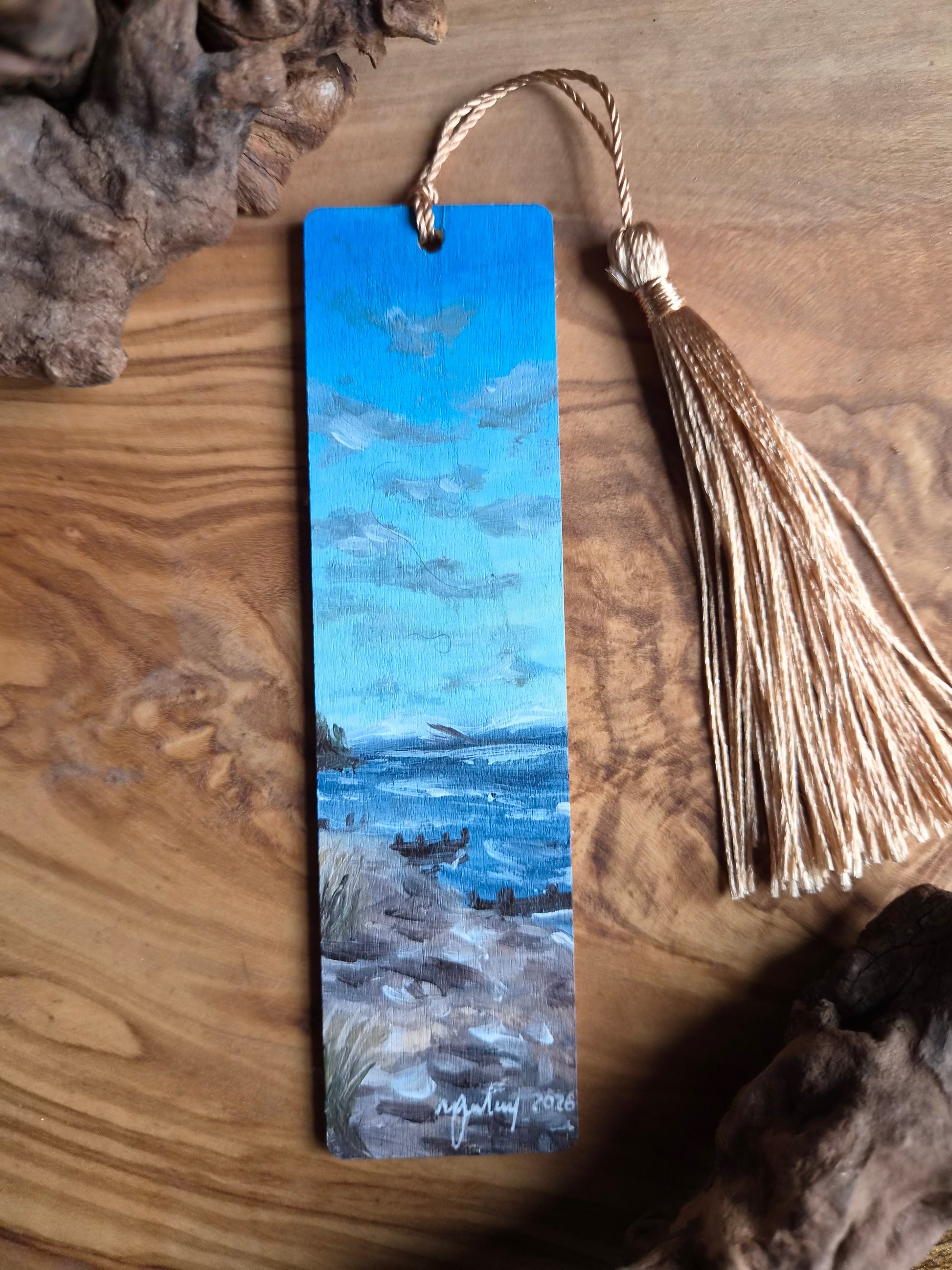 Bookmark with a beach scene design of Findhorn and tassel on a wooden surface