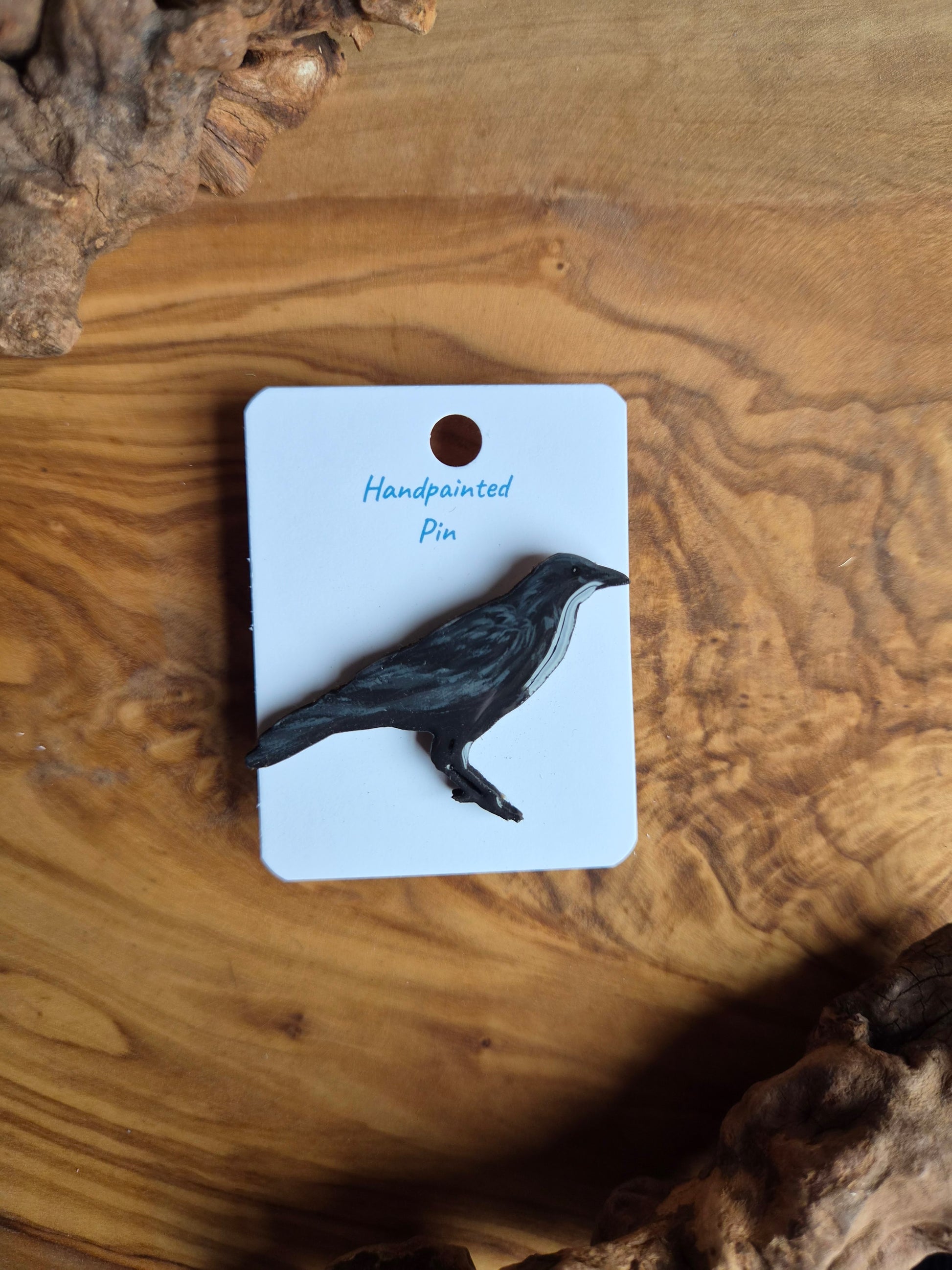 Hand-painted wooden pin badge of a perched black raven