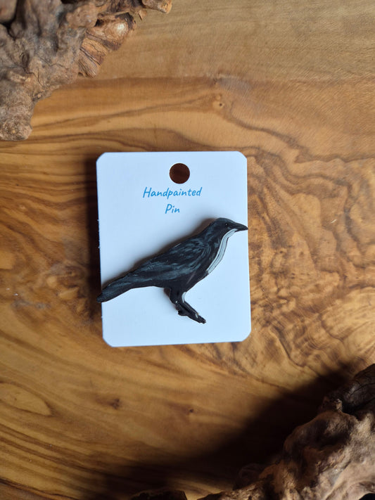 Hand-painted wooden pin badge of a perched black raven