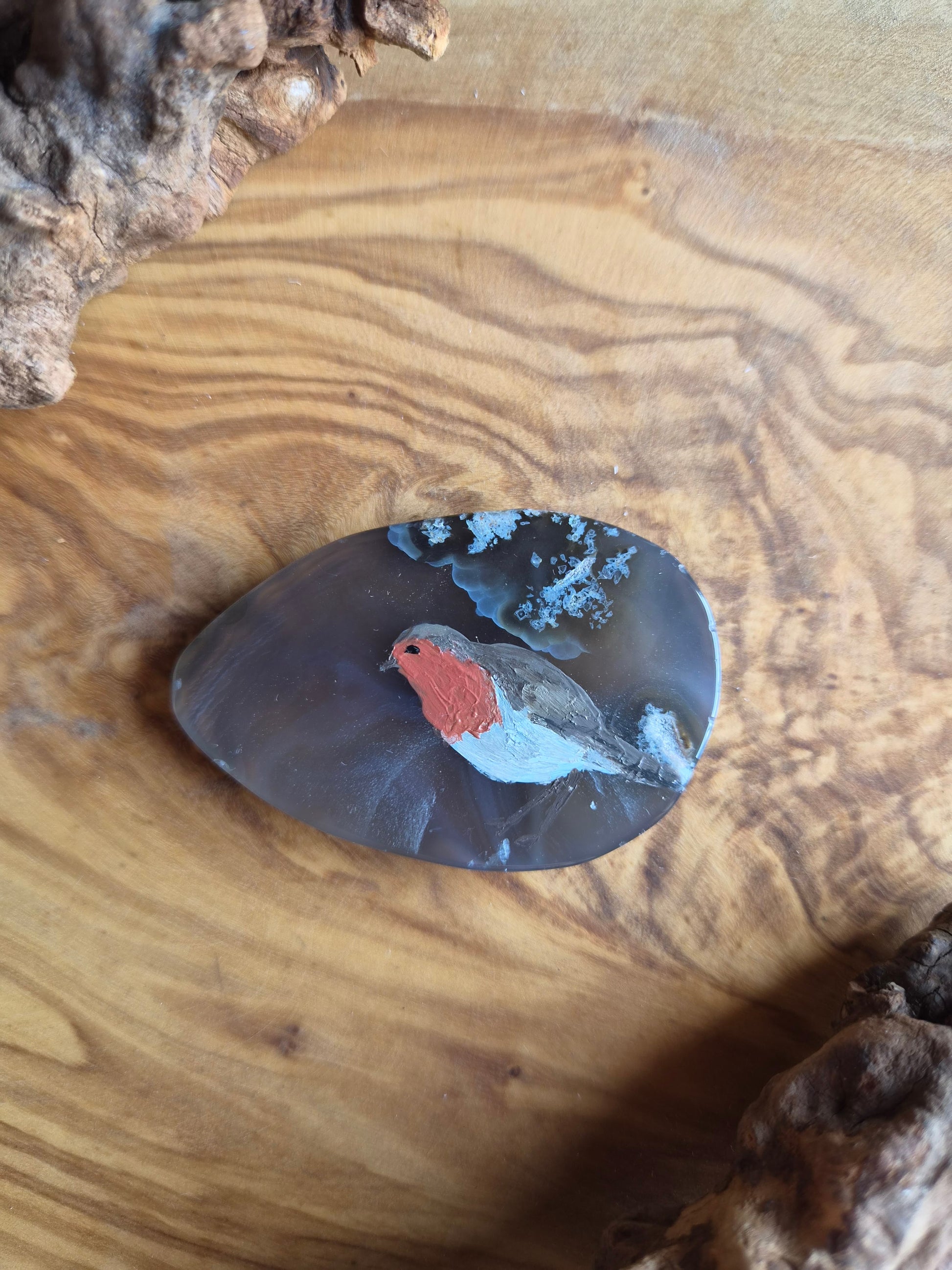a small hand-painted natural agate slice with a painting of a little robin bird on it
