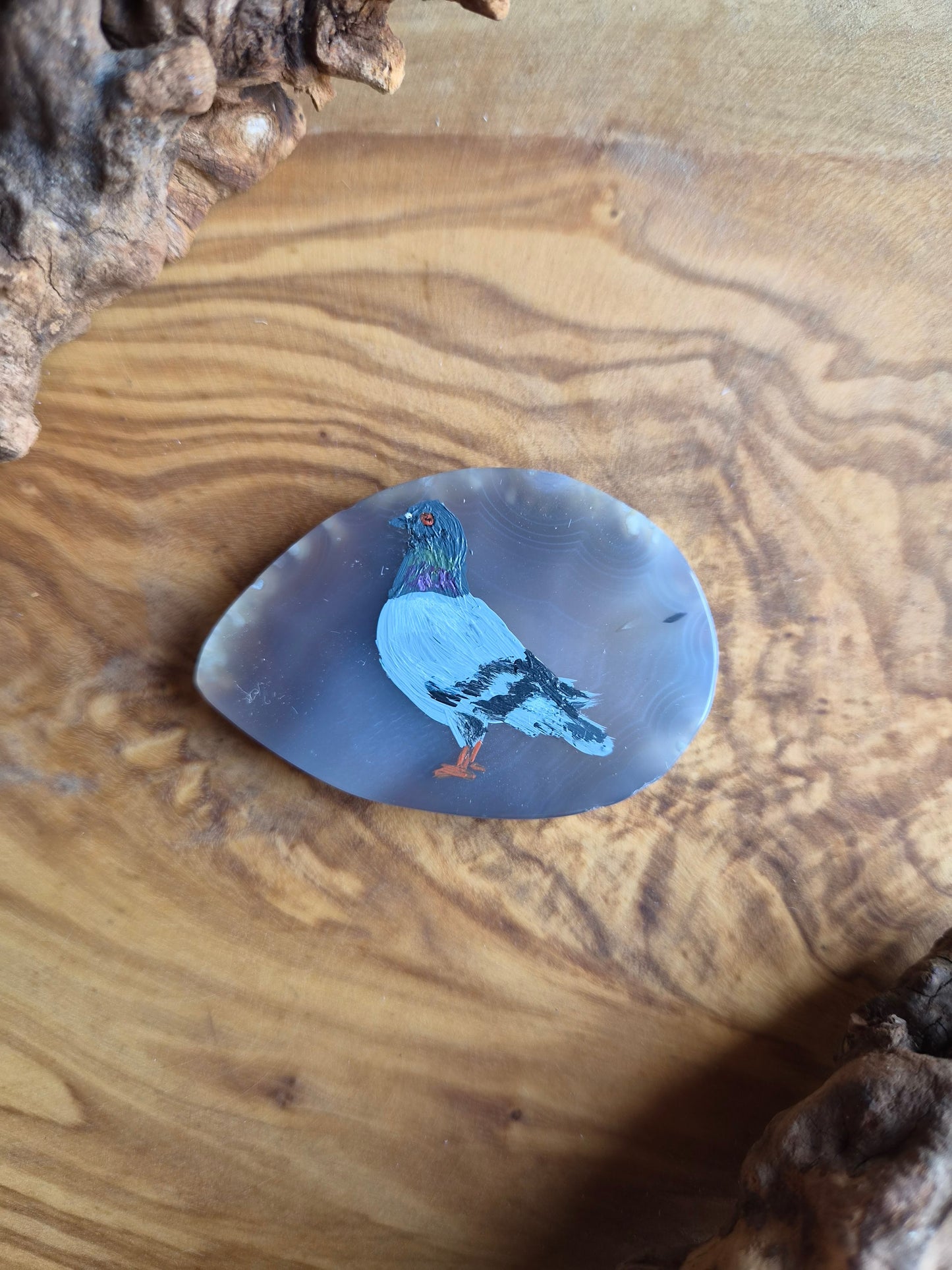 a small hand-painted natural agate slice with a painting of a pigeon bird on it