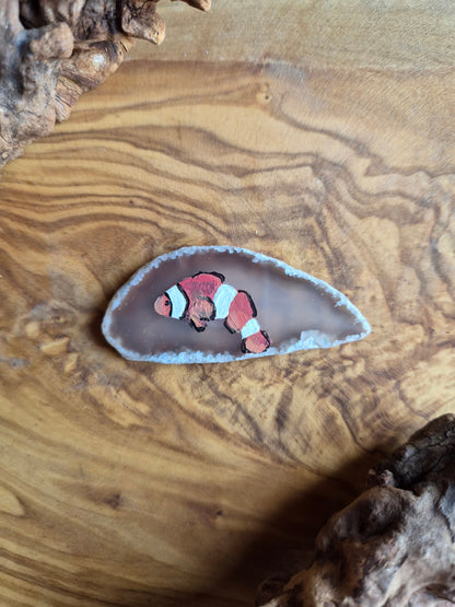 a small hand-painted natural agate slice with a painting of a clown fish on it