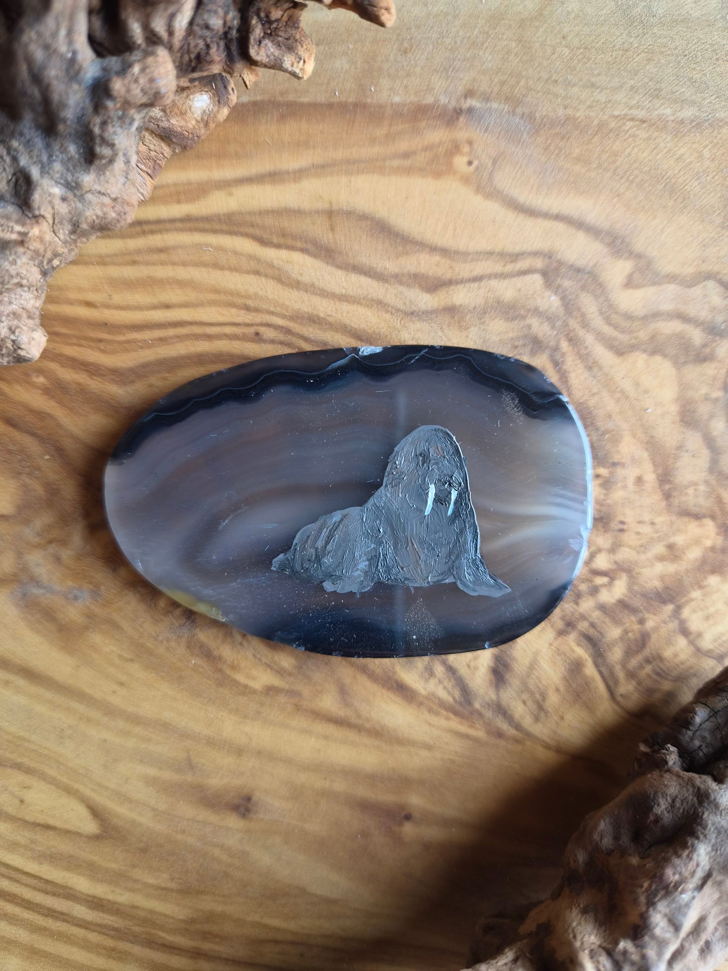 a small hand-painted natural agate slice with a painting of a walrus on it