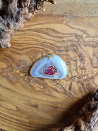 a small hand-painted natural agate slice with a painting of a strawberry on it