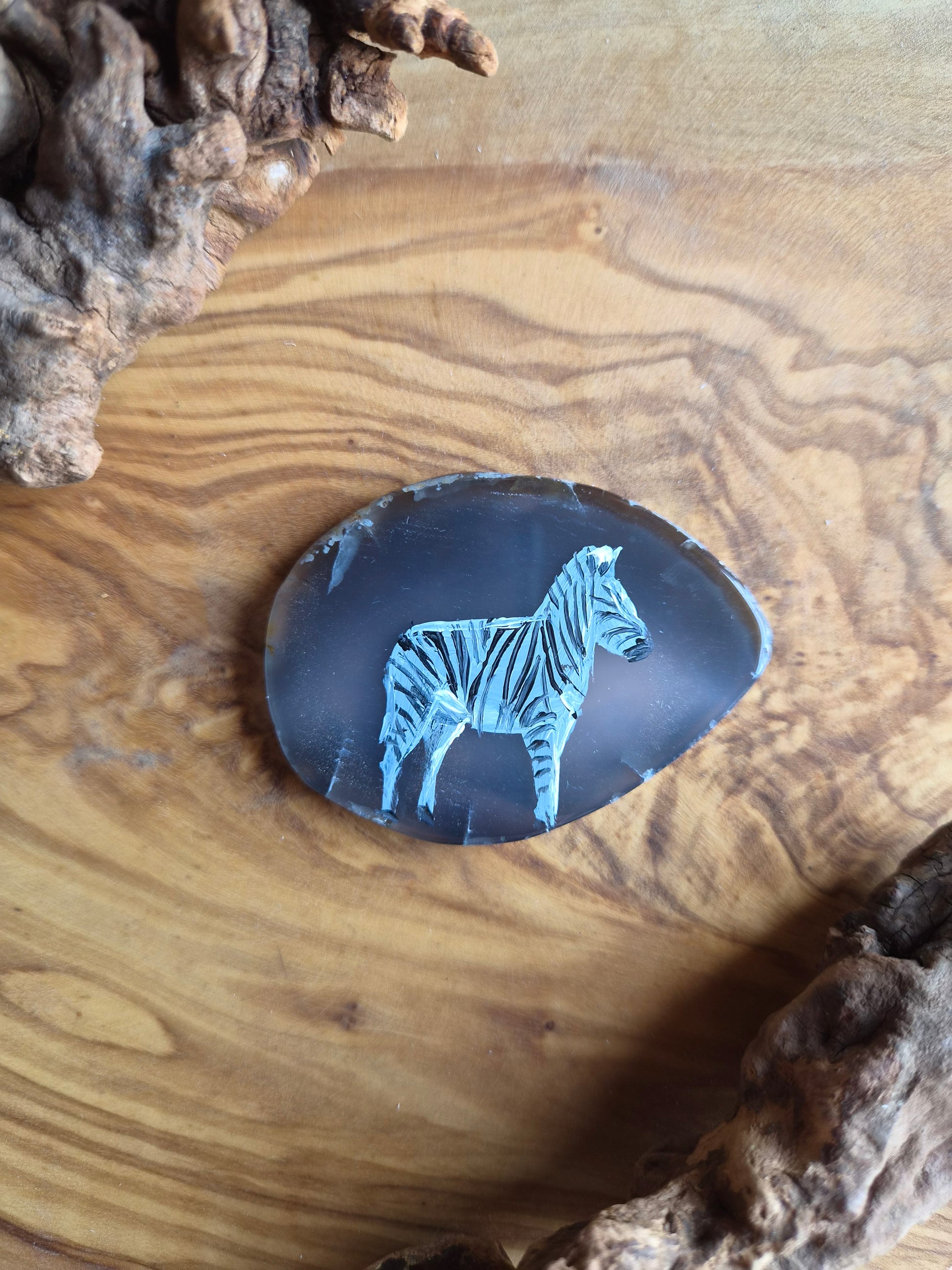 a small hand-painted natural agate slice with a painting of a zebra on it