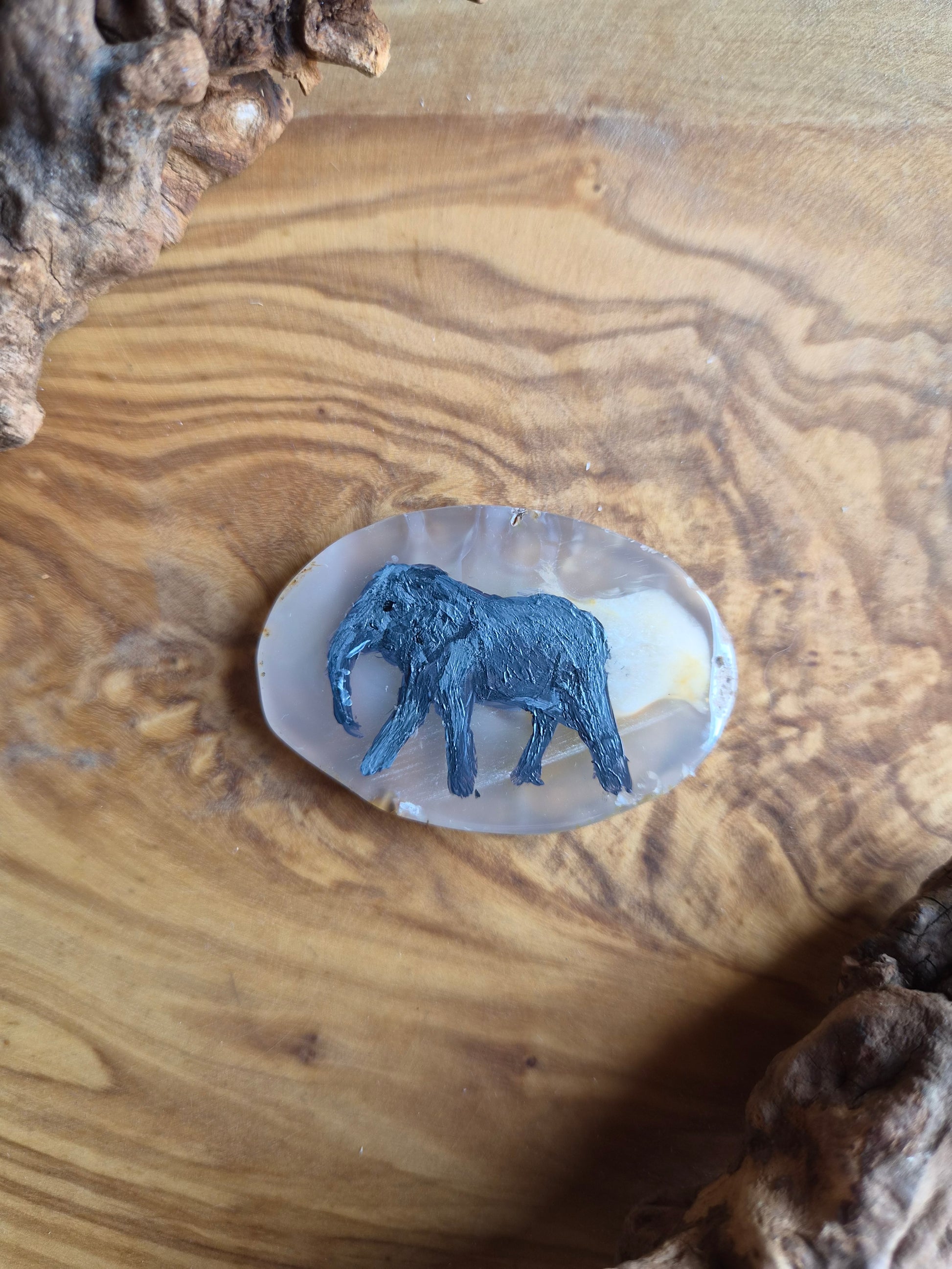 a small hand-painted natural agate slice with a painting of an elephant on it