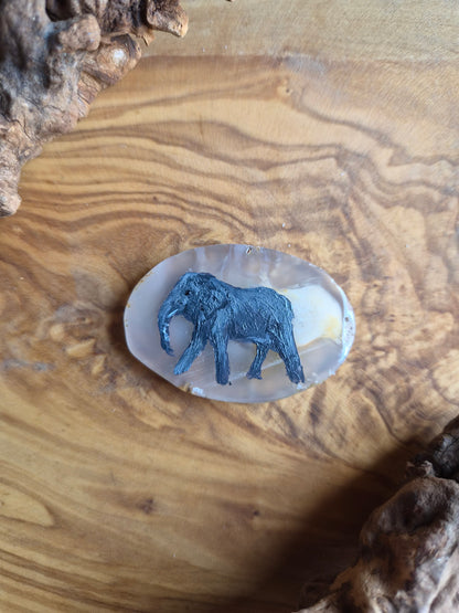 a small hand-painted natural agate slice with a painting of an elephant on it