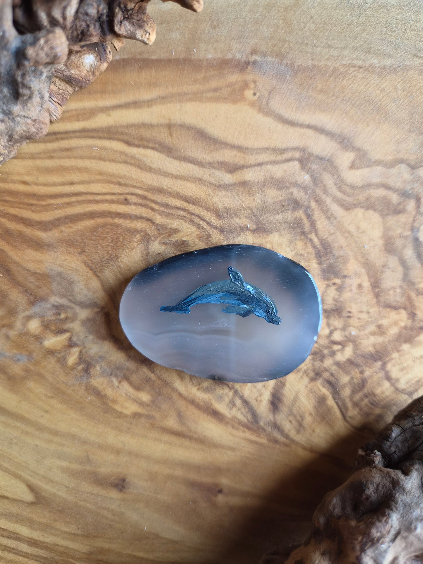 a small hand-painted natural agate slice with a painting of a dolphin on it