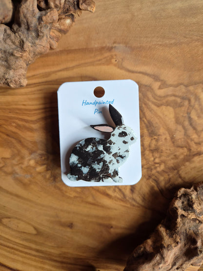 Hand-painted rabbit shaped wooden pin badge.  black and white speckled colour