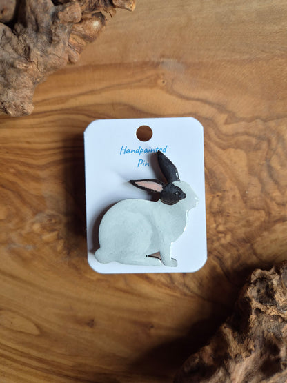 Hand-painted rabbit shaped wooden pin badge.  white with black patches on face and ears